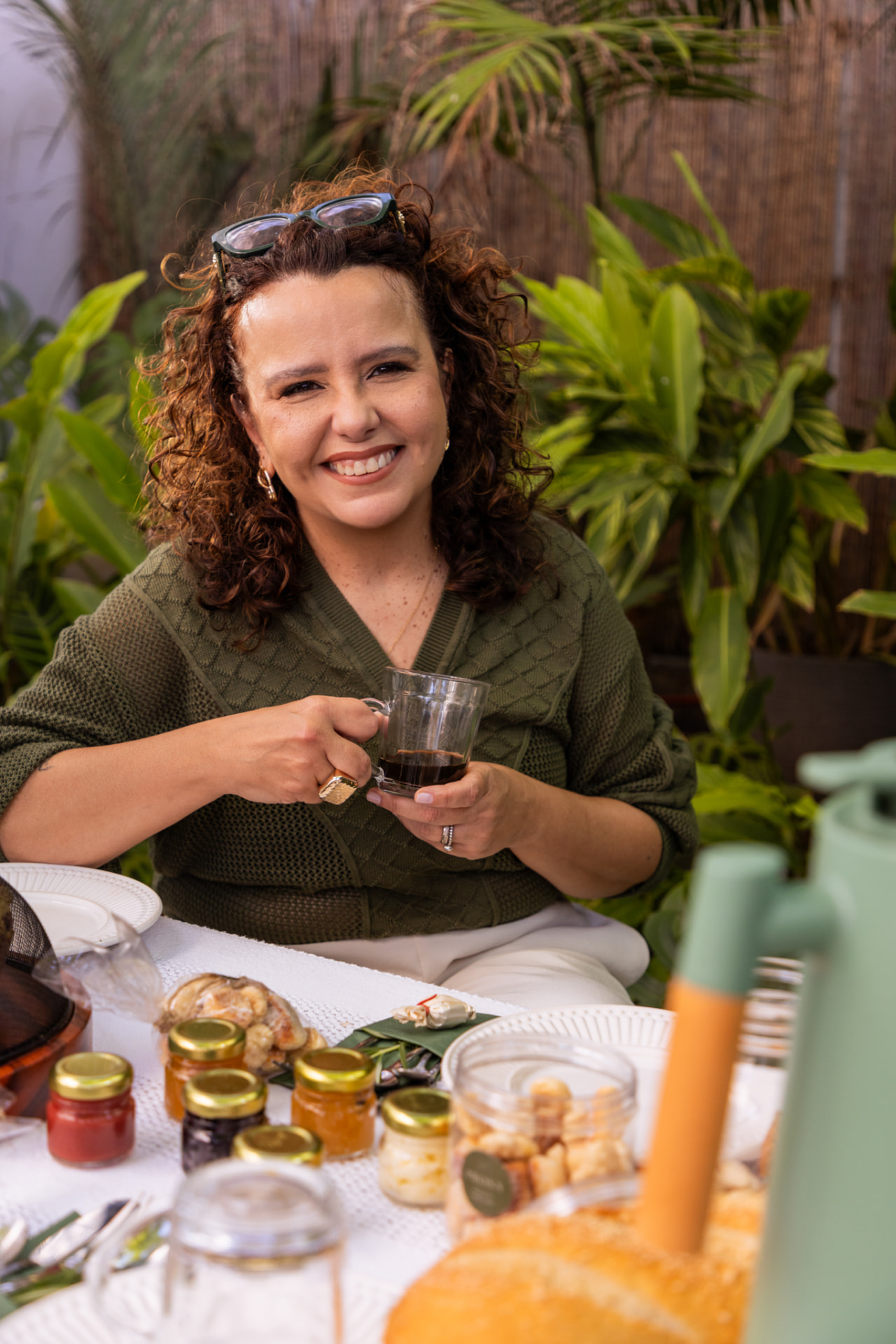 Renata, criadora do Prosa, sentada à mesa com uma xícara de café